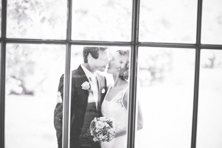 Kuss von Braut und Bräutigam hinter einem Fenster auf dem Irghof. Foto: Stefanie Danner.