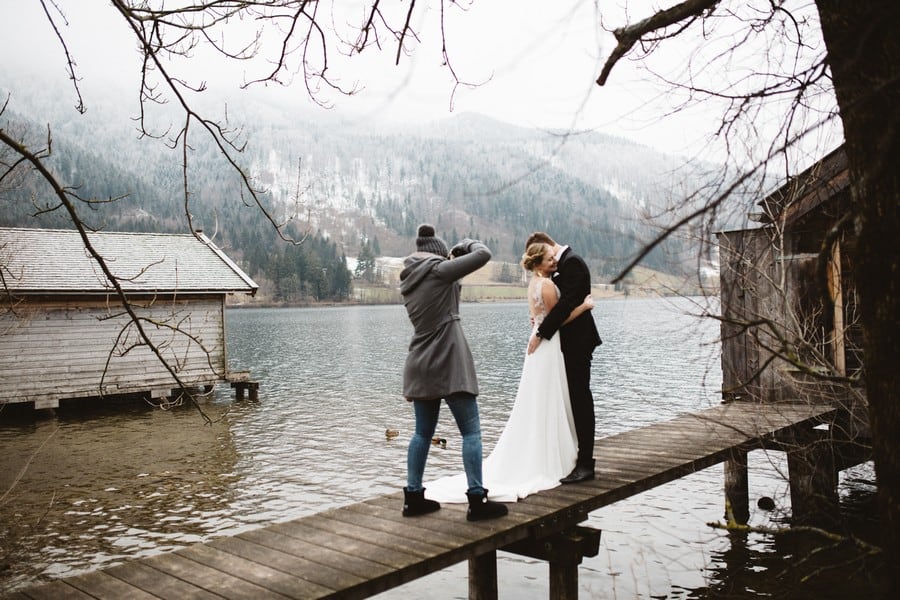 Ein Brautpaar-Shooting mit Boho-Vintage-Brautkleid mit Schleppe und Spitze auf dem Steg am Schliersee