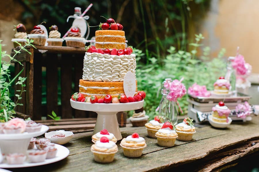 Ideen für Süßigkeiten, Obst wie Kirschen und Melonen, Gebäck, Cupcakes und Macarons für den Sweet-Table einer Hochzeit. Farbthema: Rosa, Weiß, Lila.