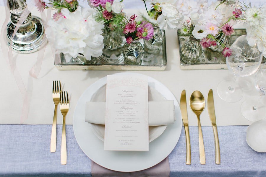 Hochzeits-Tischdeko mit kleinen Vasen und Spiegel-Tabletts in Weiß, Lila und Gold.