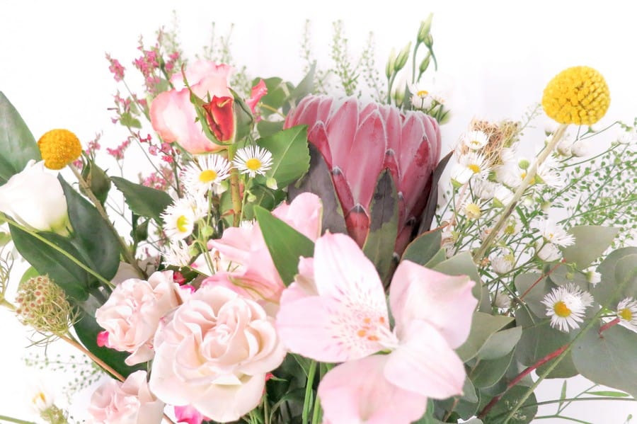 Blumenstrauß für den Trautisch mit schwarzer Vase, Protea und einem wildem Mix in Rosa und Grün