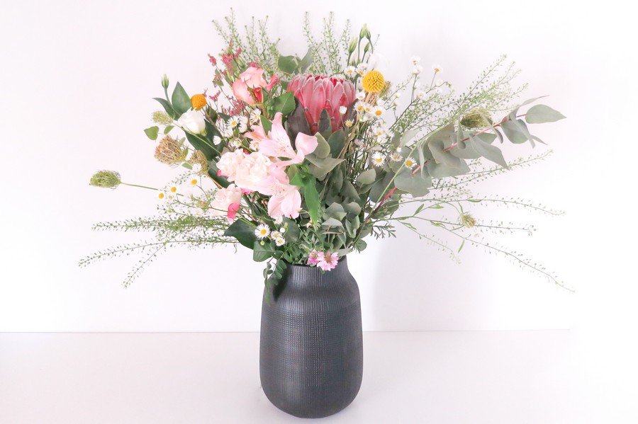 Blumenstrauß für den Trautisch mit schwarzer Vase, Protea und einem wildem Mix in Rosa und Grün